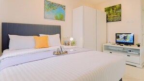 A modern hotel room with a large bed, a TV, and artwork on the walls. - Homey And Big Studio Apartment At The Wave Kuningan (Jakarta)
