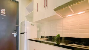 A modern kitchen with white cabinets, a black countertop, and a stainless steel sink.