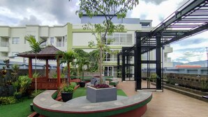 Une cour avec un belvédère, des plantes en pot et une allée couverte.