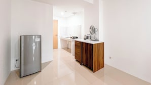 Una cocina moderna con refrigerador de acero inoxidable, armarios de madera y encimera blanca.
