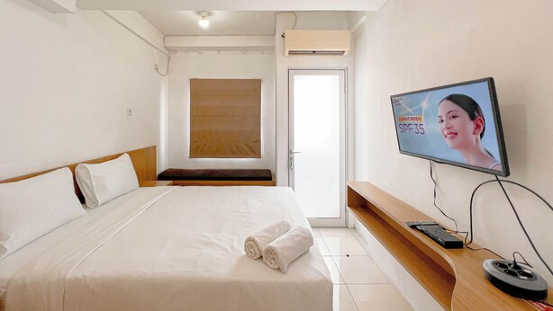 Een hotelkamer met een bed, een aan de muur bevestigde televisie en een houten bank.