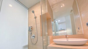 Une salle de bain moderne avec une douche à parois de verre, un lavabo blanc et un grand miroir.