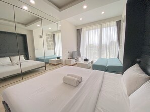 A modern hotel room with a large bed, a sofa, a TV, and a desk. - Luxurious Studio At Art Deco Apartment (Bandung)