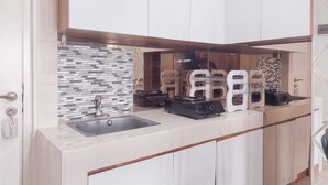 A modern kitchen with a tiled backsplash, a sink, and built-in appliances. - Homey 2Br Apartment At Urban Heights Residence (South Tangerang)