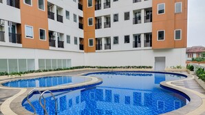 A modern building with a swimming pool and a covered patio area. - Homey 2Br Apartment At Urban Heights Residence (South Tangerang)