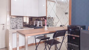 A modern kitchen with white cabinets, a wooden countertop, and a black coffee machine. - Homey 2Br Apartment At Urban Heights Residence (South Tangerang)