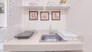 A small kitchen with a sink, a scale, and three framed pictures on the wall. - Good Place And Cozy Studio Apartment B Residence (Pagedangan)