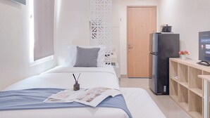 A hotel room with a bed, a television, a refrigerator, and a wooden shelf. - Good Place And Cozy Studio Apartment B Residence (Pagedangan)
