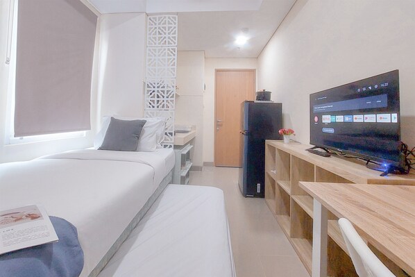 A hotel room with two beds, a TV, a desk, and a wardrobe. - Good Place And Cozy Studio Apartment B Residence (Pagedangan)