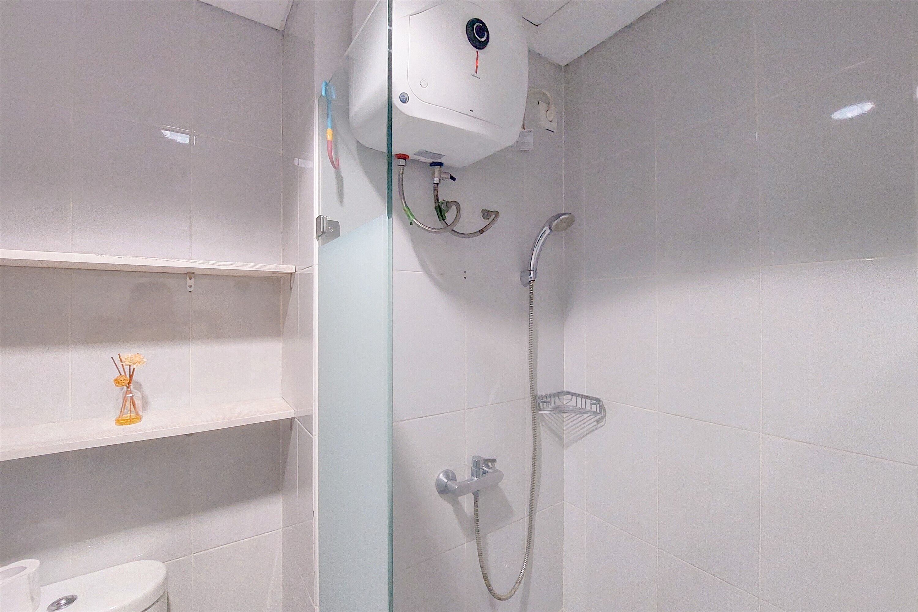 Un baño moderno con cabina de ducha de vidrio, un inodoro y una repisa con un pequeño florero.