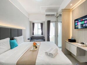 Ein modernes Hotelzimmer mit einem großen Bett, einem Nachttisch, einem an der Wand befestigten Fernseher und Blick auf die Stadt durch das Fenster.