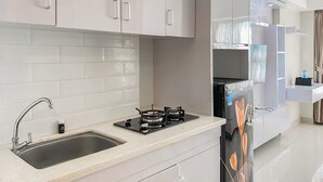 A modern kitchen with white cabinets, a stainless steel sink, a gas stove, and a refrigerator. - Good Place And Comfortable Studio Apartment Springlake Summarecon Bekasi (Bekasi)