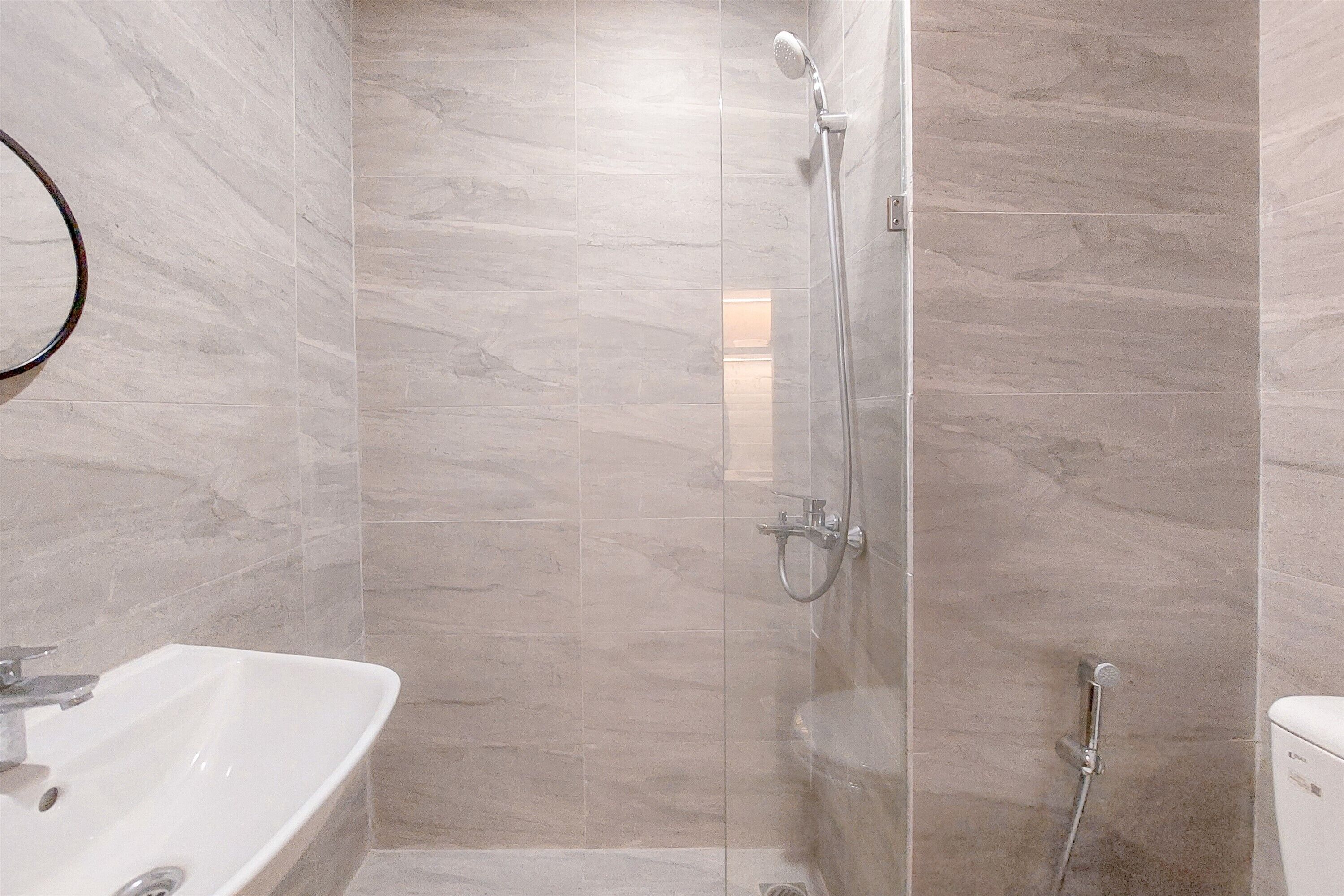 A modern bathroom with a glass-enclosed shower, a white sink, and a toilet.