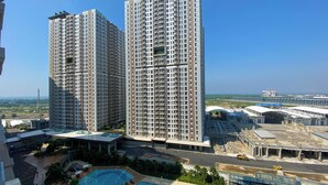 Een hoog appartementencomplex met meerdere balkons, een zwembad en een bouwplaats in de buurt.