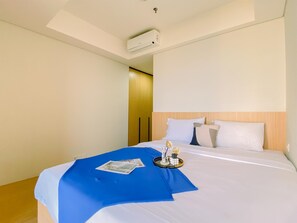 Ein Hotelzimmer mit Bett, blauer Tagesdecke, Tablett mit Dekoration und Klimaanlage an der Decke.