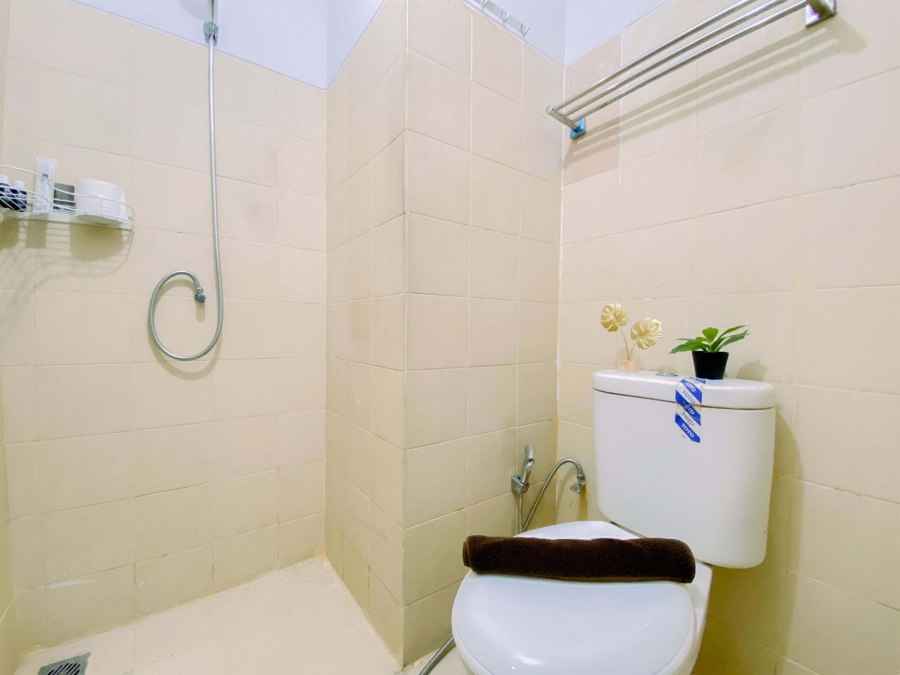 Casa de banho com chuveiro, sanita e um espaço com produtos de higiene pessoal.