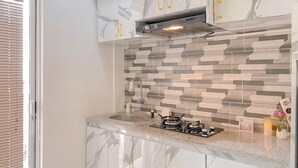 A modern kitchen with marble cabinets, a stainless steel range hood, and a patterned backsplash. - Homey And Well Furnished Studio At Bassura City Apartment (Jakarta)