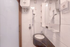 A bathroom with a sink, mirror, and shower. - Cozy Living Studio At Sky House Bsd Apartment (Pagedangan)