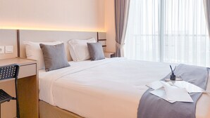 Hotellihuone, jossa on suuri sänky, työpöytä ja tuoli.