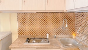 A kitchen with a gas stove, sink, and tiled backsplash. - Good Place And Homey At 2Br Kebagusan City Apartment (Jakarta)