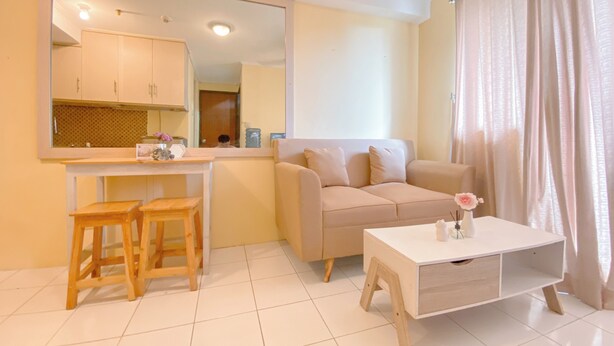 A modern living room with a beige sofa, a white coffee table, and wooden stools. - Good Place And Homey At 2Br Kebagusan City Apartment (Jakarta)