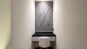 A modern bathroom with a grey tiled wall, a black countertop, and a white chair.