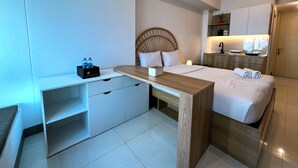 A modern hotel room with a bed, bedside table, desk, and built-in wardrobe. - Compact And Best Choice Studio At Anderson Supermall Mansion Apartment (Surabaya)
