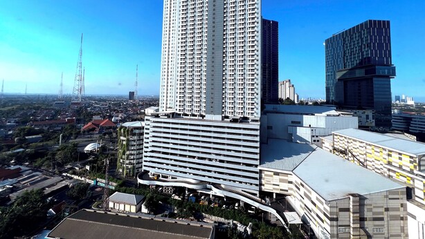 A high-rise building with multiple floors, surrounded by other buildings and a clear sky. - Compact And Best Choice Studio At Anderson Supermall Mansion Apartment (Surabaya)