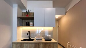 A compact kitchen with a wooden countertop, a black faucet, a toaster, and a small shelf with kitchen items. - Compact And Best Choice Studio At Anderson Supermall Mansion Apartment (Surabaya)