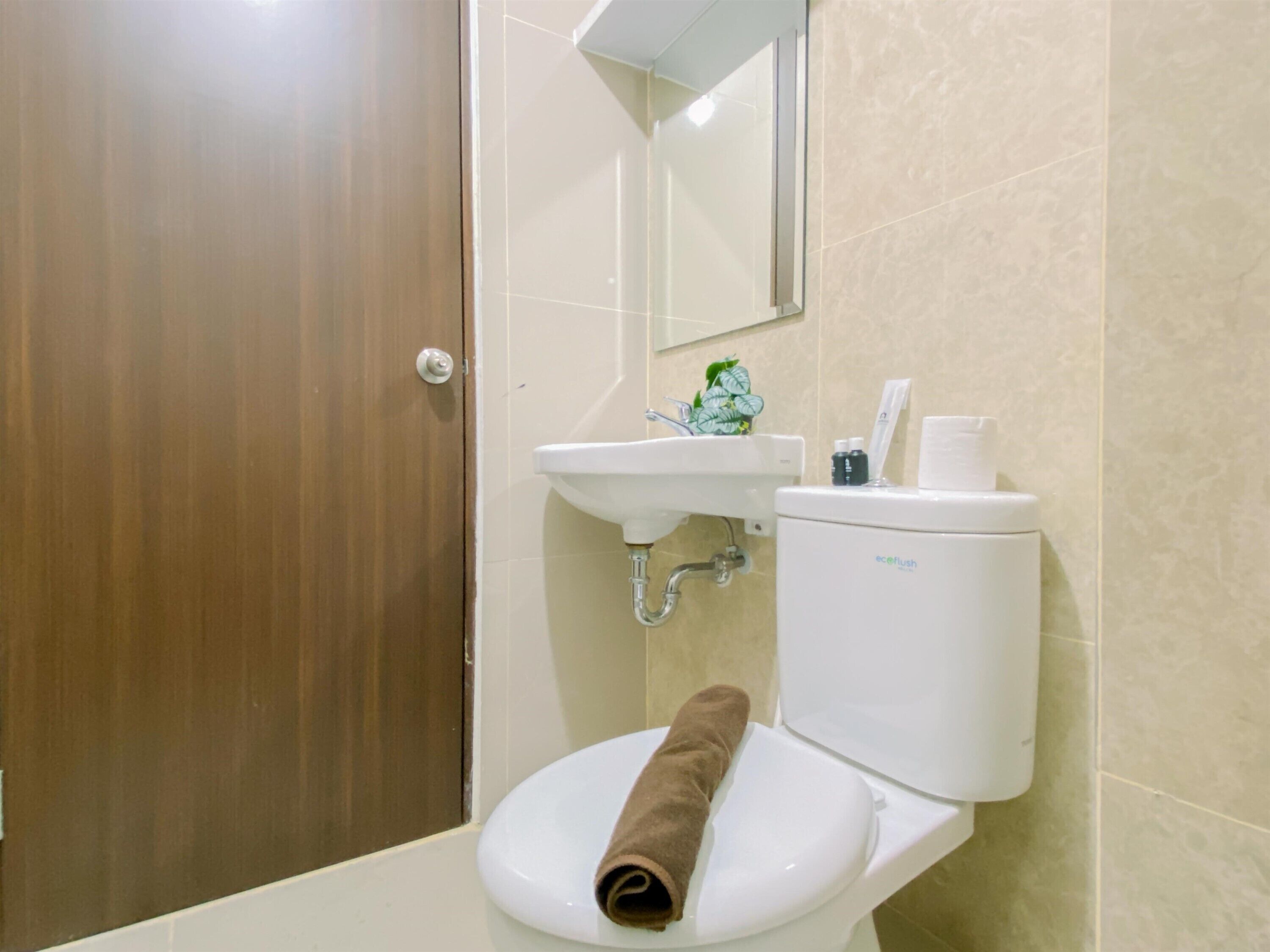 A bathroom with a wooden door, a white sink, a toilet, and a mirror above the sink.