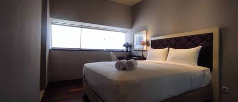 Una habitación de hotel con una cama, un escritorio, una silla, una lámpara y una ventana.