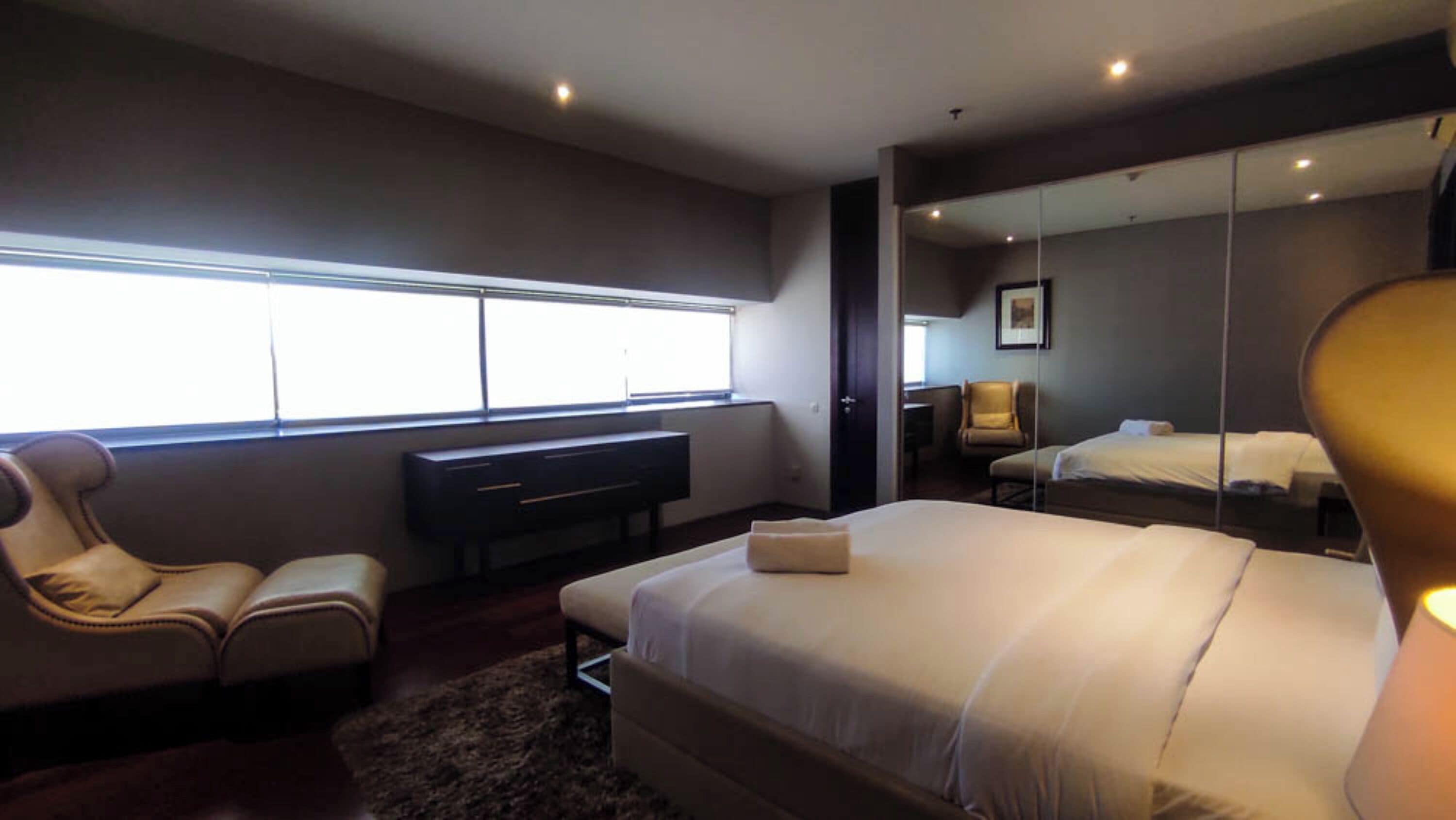 Une chambre d’hôtel moderne avec un grand lit, un bureau, une chaise et une fenêtre.