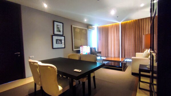 Ein modernes Hotelzimmer mit Esstisch, Stühlen, einer Couch und einem Fernseher.