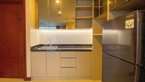 A modern kitchen with a built-in sink, a stainless steel refrigerator, and a wooden door. - Spacious And Homey 2Br Apartment With Private Lift At The Kencana Residence (Jakarta)