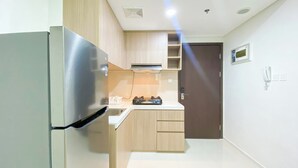 Une cuisine compacte équipée d’un réfrigérateur en acier inoxydable, de meubles de rangement en bois, d’une cuisinière à gaz et d’un four à micro-ondes.