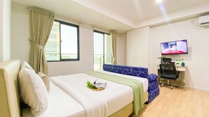 Une chambre d’hôtel avec un lit, un bureau, une télévision et une fenêtre avec des rideaux.