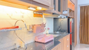 A modern kitchen with a stainless steel refrigerator, a sink, and a dish rack. - Studio At Transpark Juanda Bekasi Timur Apartment (Bekasi)
