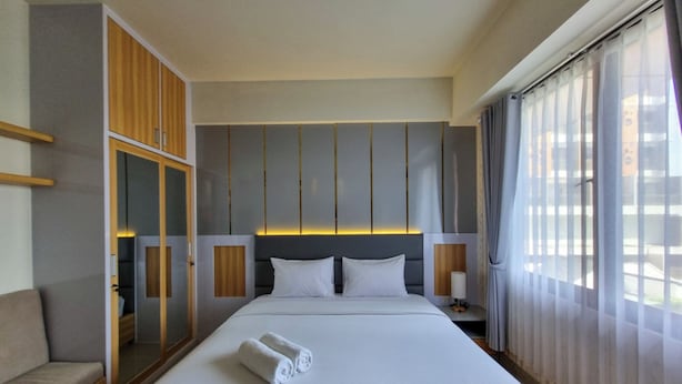 Ein Hotelzimmer mit einem großen Bett, einem Kleiderschrank, einem Nachttisch und einem fenster mit Vorhängen.