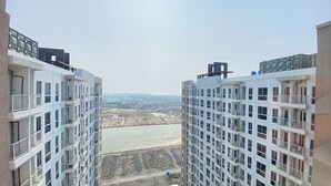 Uitzicht tussen twee hoog gebouwen met balkons, uitkijkend op een bouwplaats en een waterlichaam.
