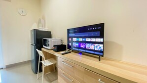 A kitchenette with a microwave, refrigerator, and a flat-screen TV displaying streaming services. - Minimalist And Compact Studio (No Kitchen) At Apartment B Residence (Pagedangan)