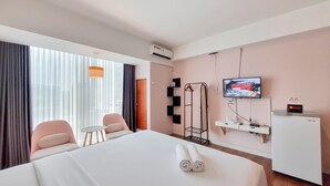 Une chambre d’hôtel avec un lit, une télévision, un bureau et une chaise.