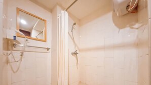 Une petite salle de bain carrelée, équipée d’une douche, d’un miroir et d’un porte-serviettes.