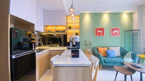 Eine moderne Küche mit einer zentralen Kochinsel, ein Essbereich mit Tisch und Stühlen sowie ein Wohnzimmer mit Sofa und Couchtisch.