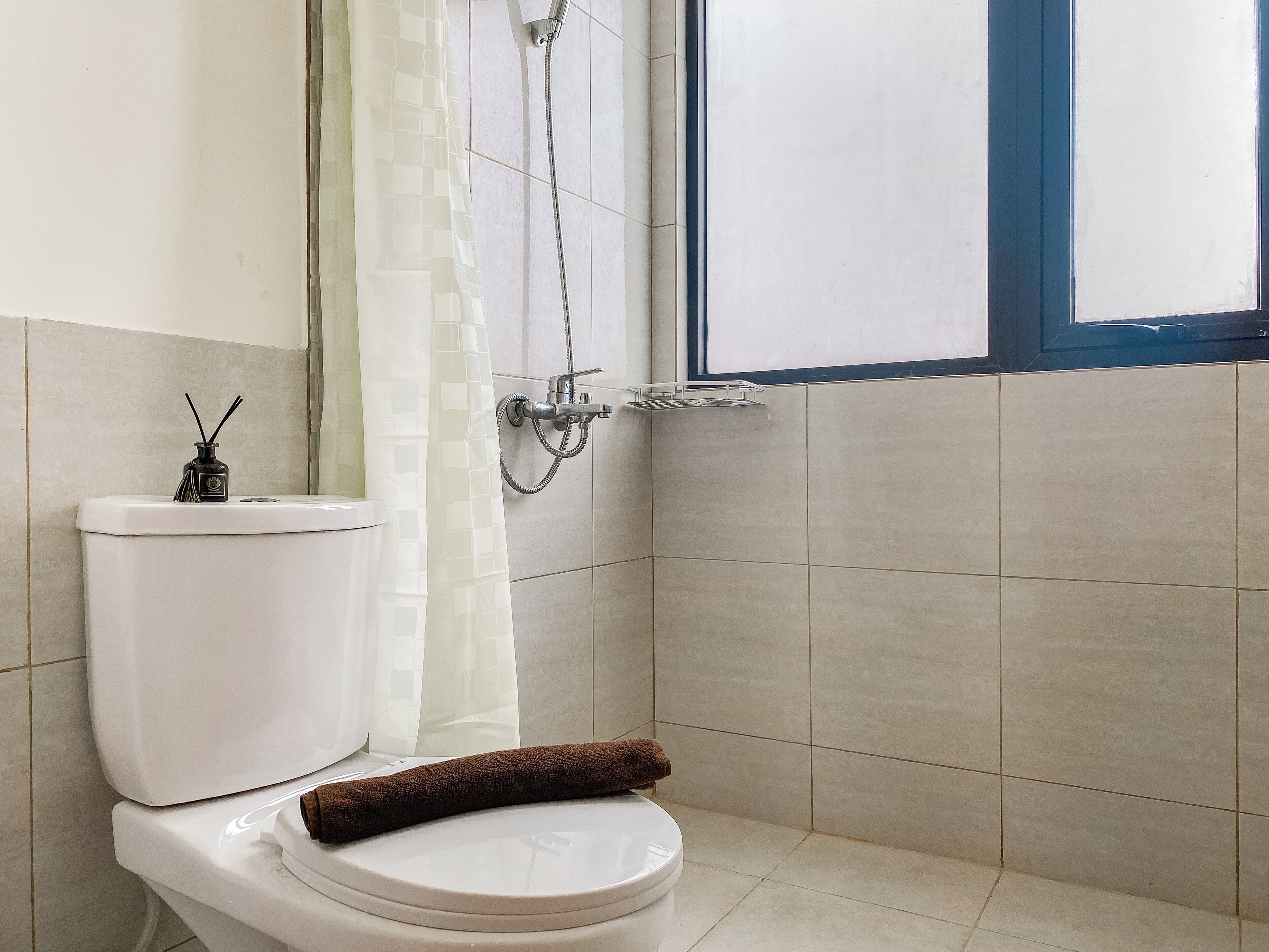 A bathroom with a toilet, a shower, and a window.