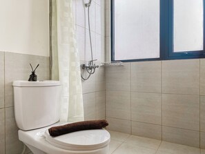Une salle de bain avec des toilettes, une douche et une fenêtre.