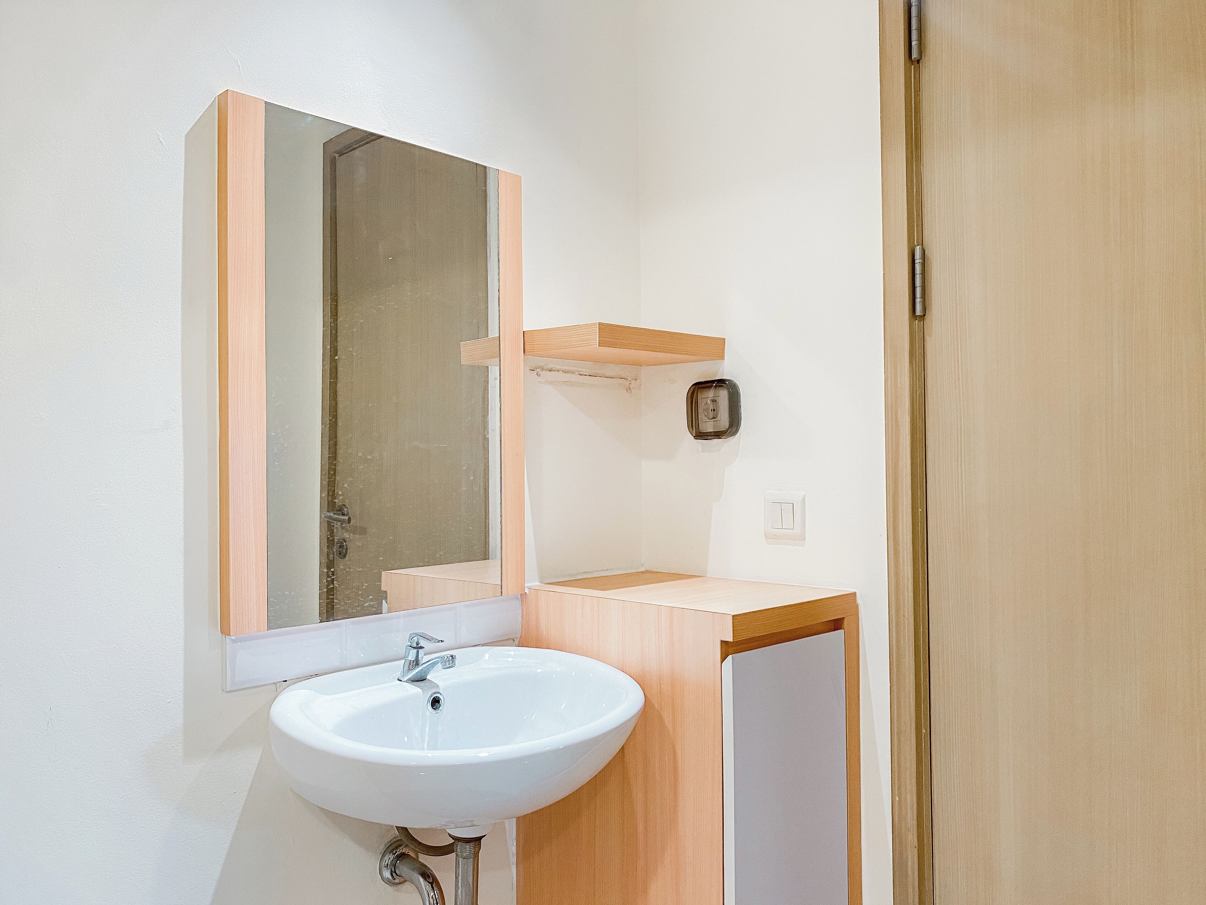 Une salle de bain avec un lavabo blanc, un miroir et un meuble-lavabo en bois.