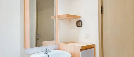 A bathroom with a white sink, a mirror, and a wooden vanity.