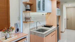A compact kitchen with a sink, countertop, and wooden cabinets. - Comfort 2Br At Meikarta Apartment Cikarang (Cikarang)