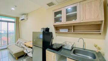 Cocina compacta con refrigerador, lavamanos y armarios de madera.