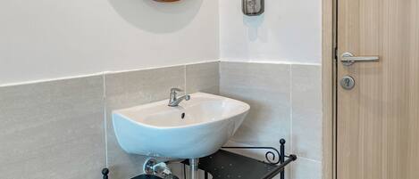 Un baño con un lavabo blanco, un espejo redondo y una puerta de madera.
